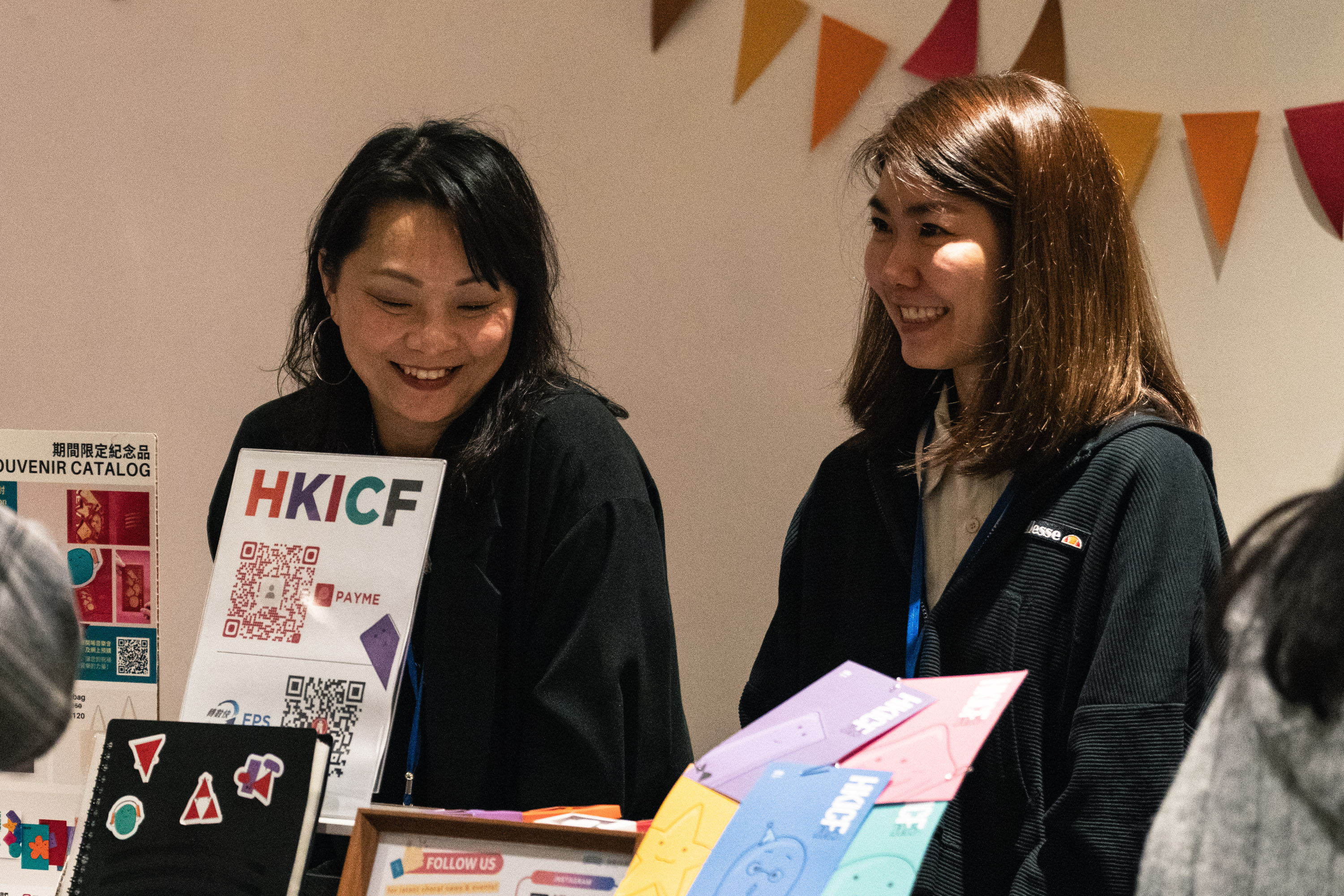 Two volunteers welcoming visitors at an HKICF information desk
